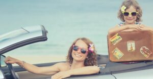 Mother and daughter smiling from car on vacation