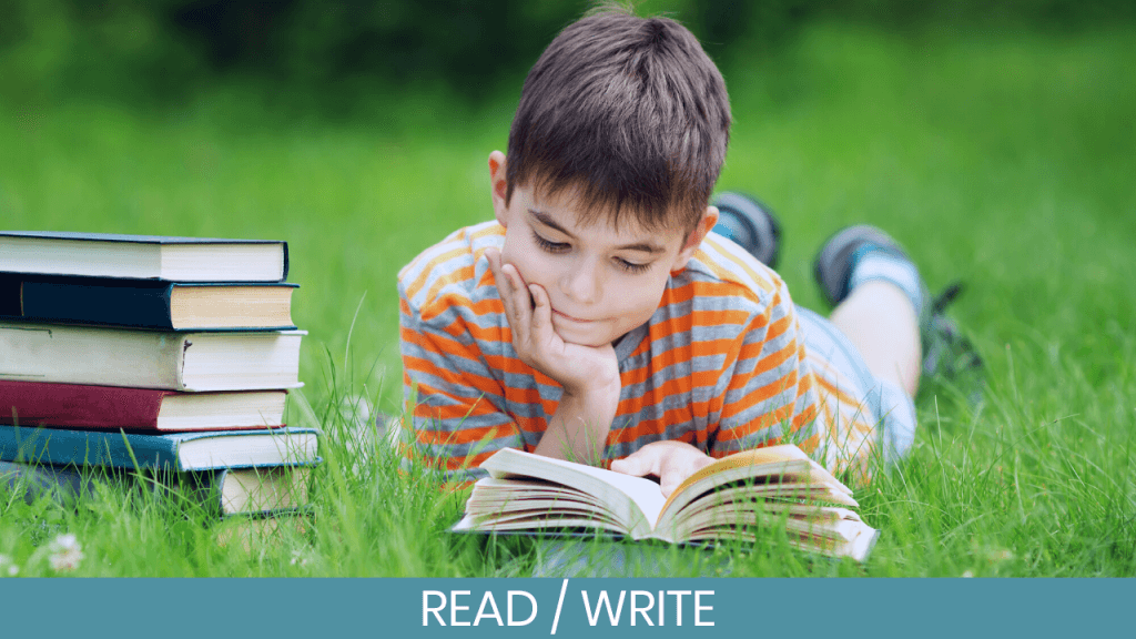 Boy lying on grass reading a book