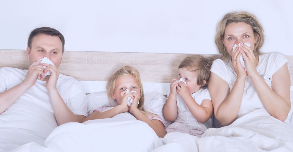 Family in bed sick, blowing their nove
