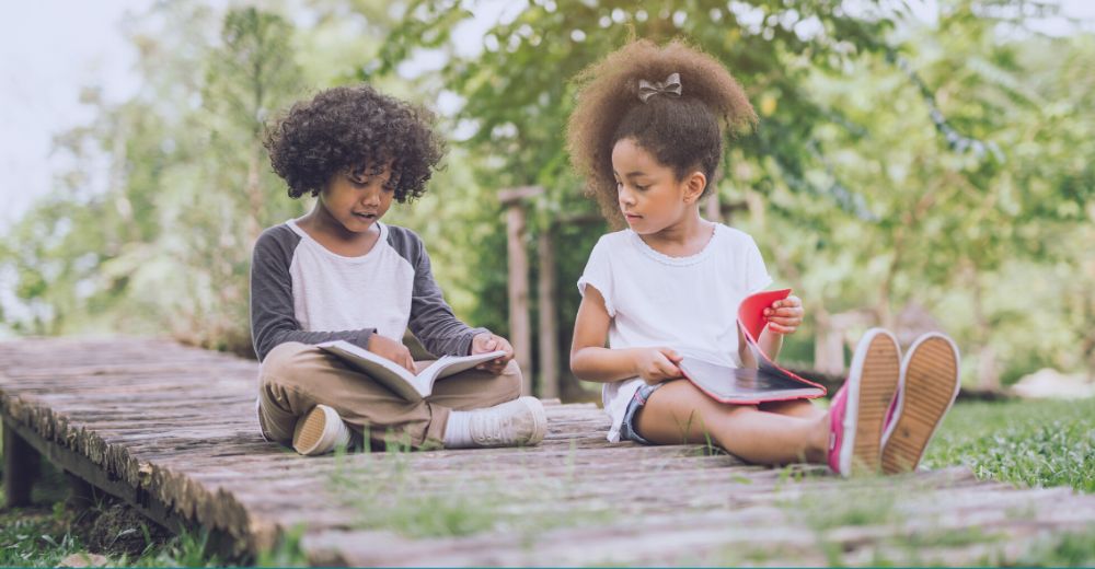 Boy and girl reading a book outdoors