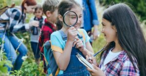 Girl looking at another girl with a magnifying glass