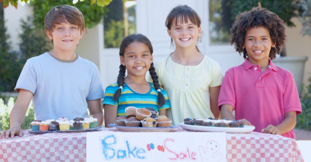 Children at bake sale smiling at camera