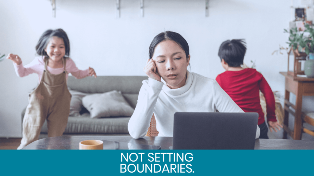 Woman looking worried at computer with kids playing behind her